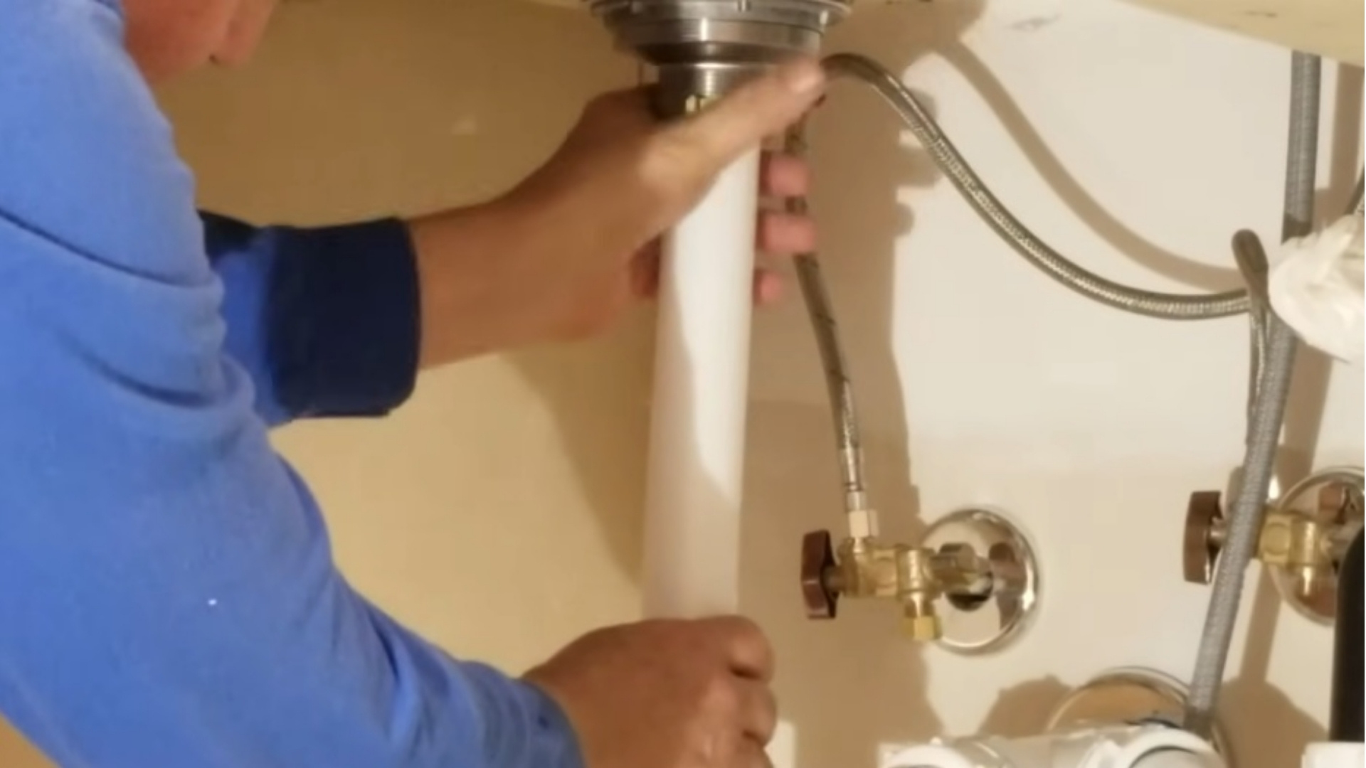Katy Apex Plumbing technician repairing a fixture under a kitchen sink in Katy, TX
