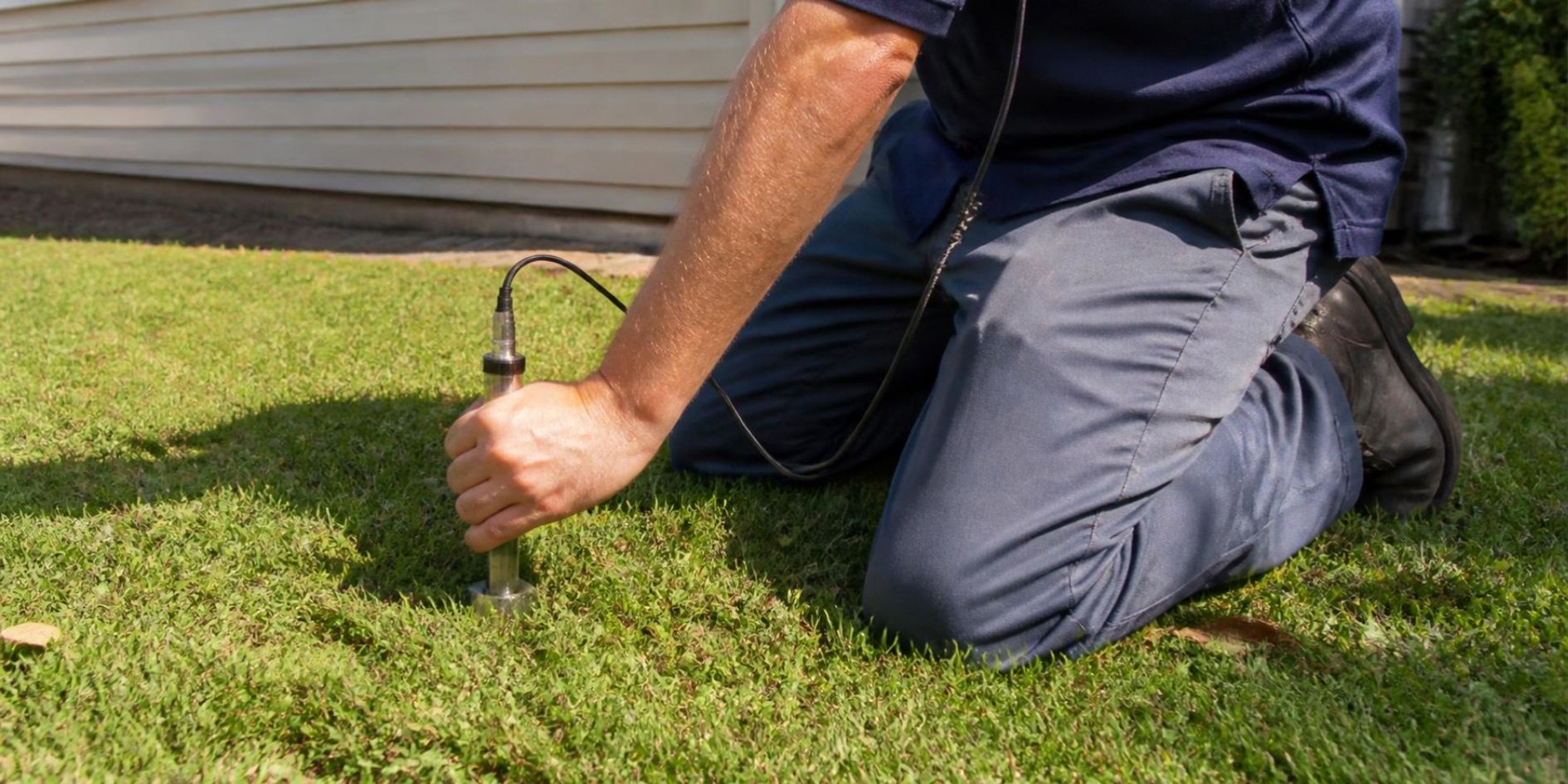 Plumber using acoustic leak detection equipment on a residential lawn